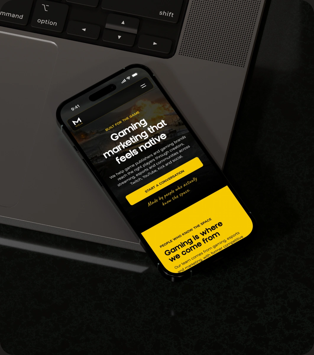 Miela gaming expertise page on a phone beside a laptop